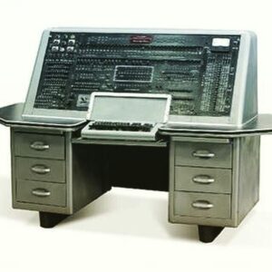 Second-generation computer with a large control panel featuring switches, buttons, and indicator lights, accompanied by a keyboard and desk setup