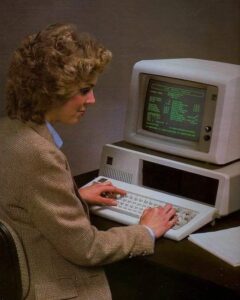 Third-generation computer with a CRT monitor displaying text, a keyboard, and a woman typing, representing the improved usability of computers in the 1970s